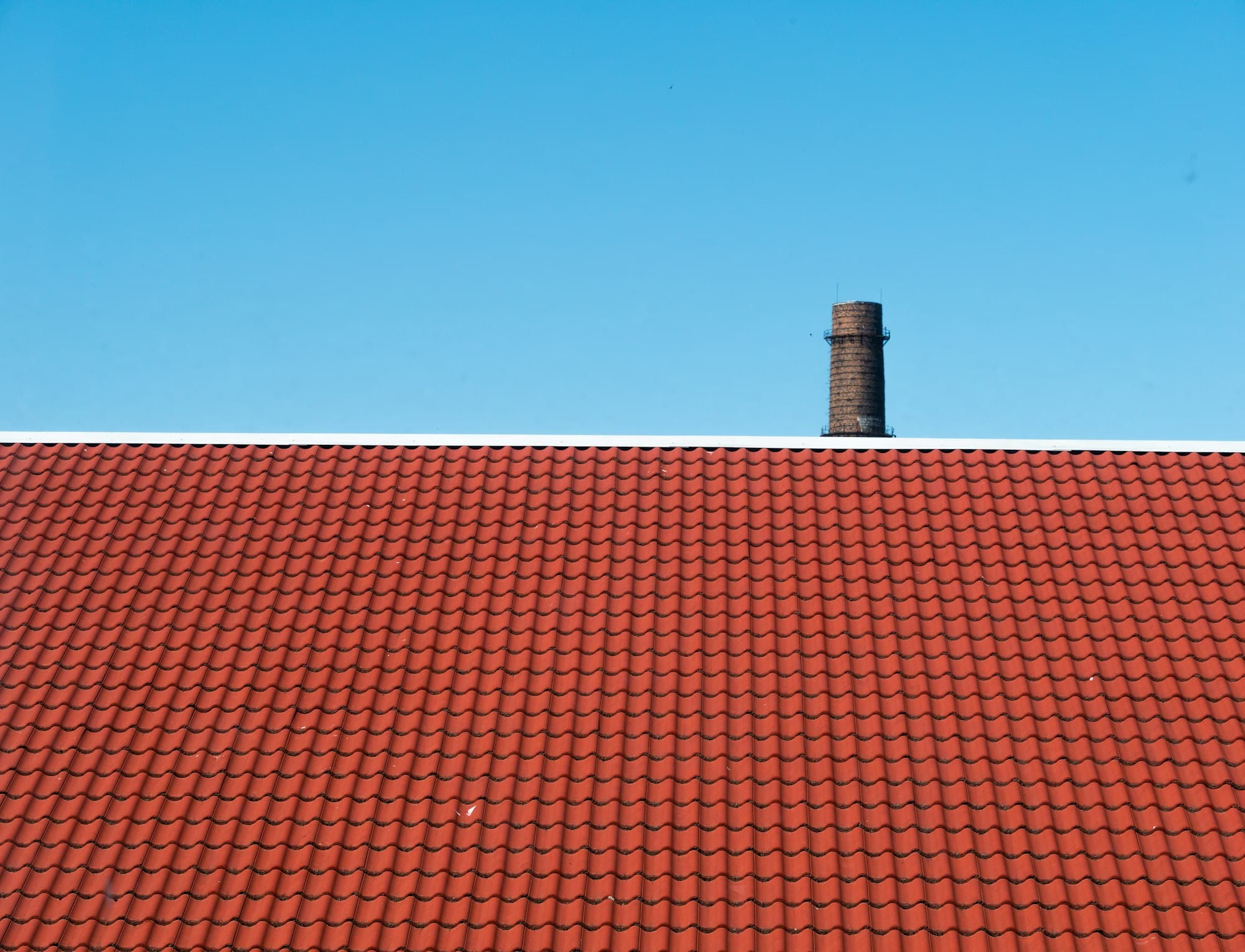 Freshly coated red tile roof against a bright blue sky