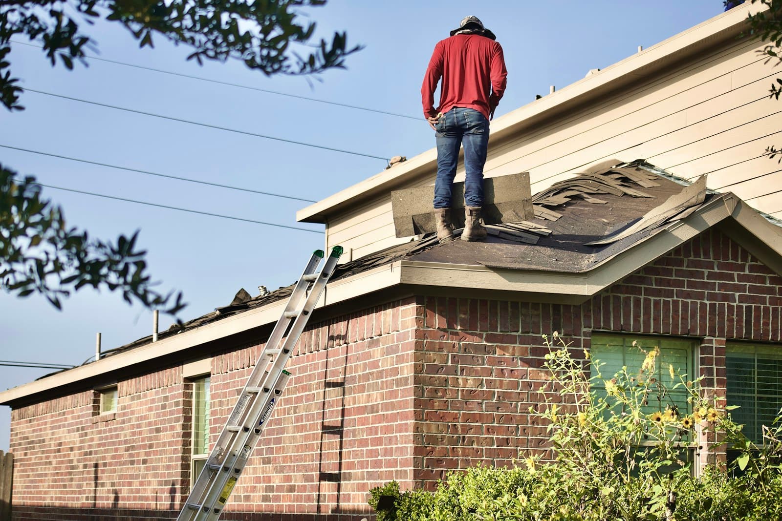 Tradesperson standing on the roof of a brick home during an inspection